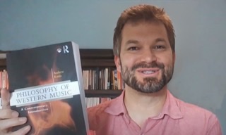 An enhanced color photograph of Andrew Kania holding up his book "The Philosophy of Western Music."