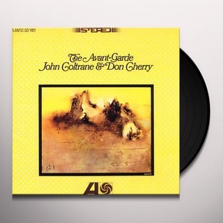 The very all over yellow album cover for "The Avante Garde" LP record by John Coltrane and Don Cherry with an abstract painting of amorphous brown and yellow shapes surround by a black border and the title with their two names written above the box in curly font with the black LP record poking out from the cover on the right side.