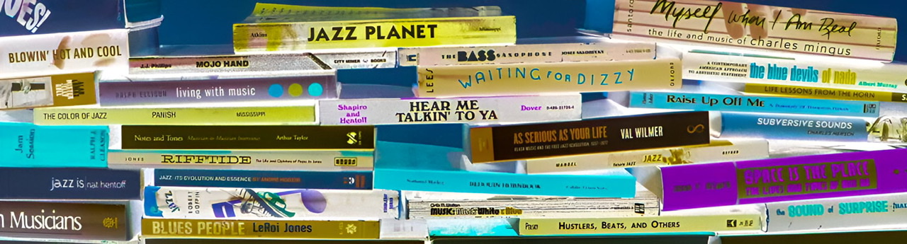 An enhanced color photograph of books on jazz laid on top of each other horizontally.