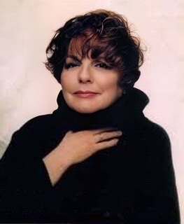 A color photograph of Carol Sloane in middle age wearing a black turtleneck with her right hand held just under her throat.