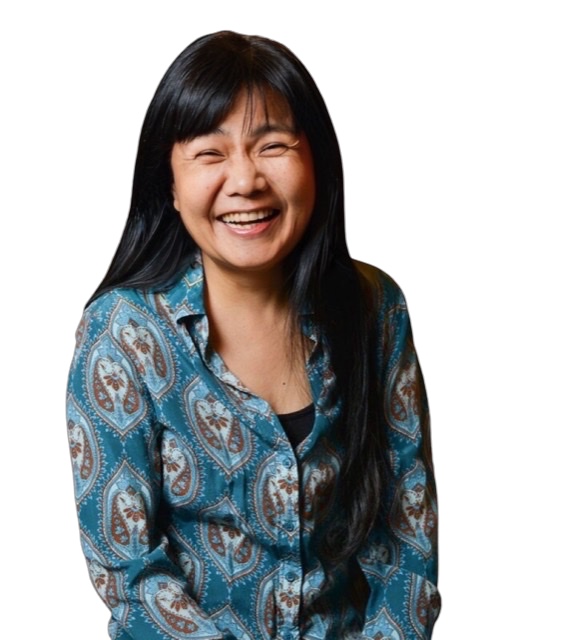An enhanced color photograph of a big smiling Satoko Fujii wearing a blue shirt with brown circular graphics all over it.