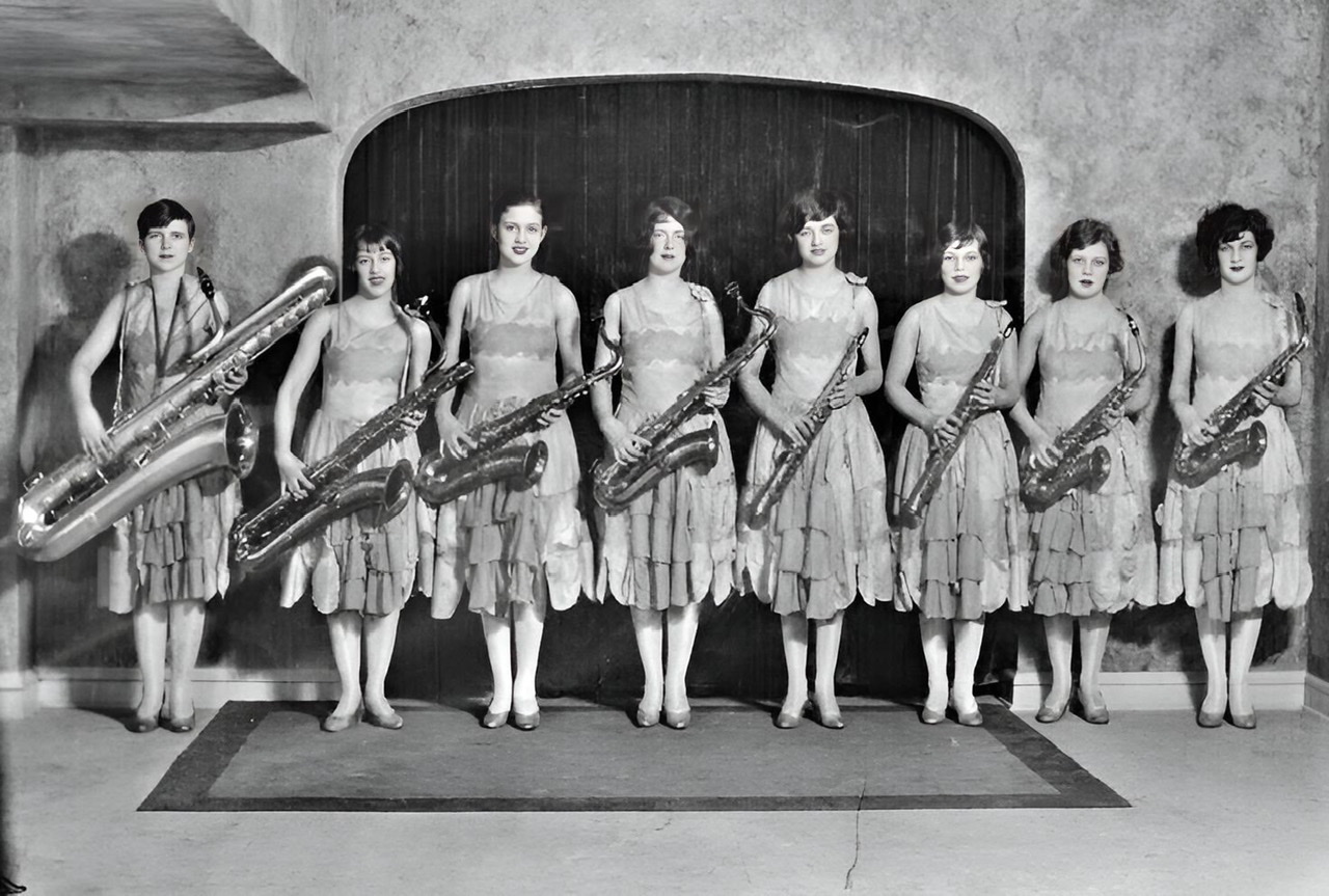 An enhanced black and white photograph of The Ingenues holding eight saxophones.