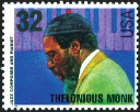 A color image of a U.S. stamp worth 32 cents with the left profile of Thelonious Monk's torso and his head wearing a beanie hat with him wearing a bright green jacket and a blue and purple piano keyboard behind his head in the background.
