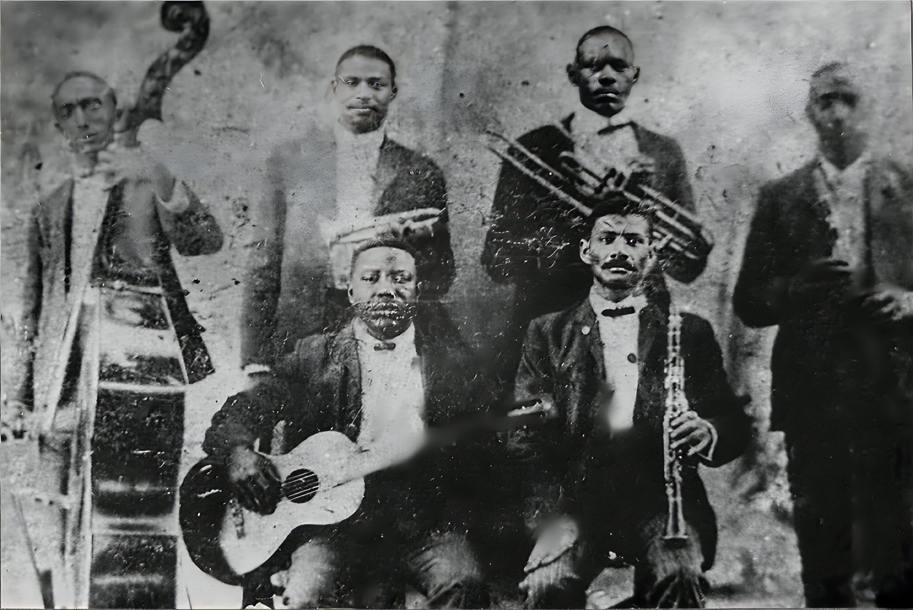 An enhanced black and white  photograph of the Buddy Bolden band with Bolden second from left holding his trumpet at his waist.